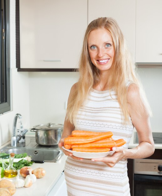 Happy pregnant woman holding carrots