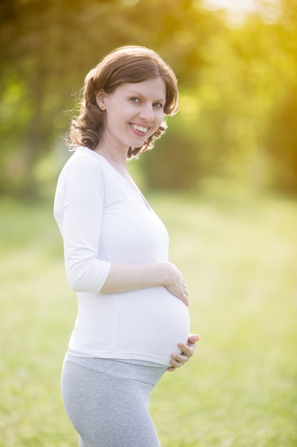 Free photo happy pregnant woman on late pregnancy period walking in park