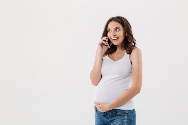 Happy pregnant woman talking by mobile phone