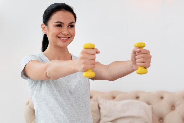 Happy pregnant woman using yellow weights