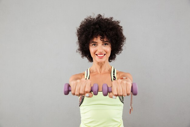 Donna graziosa felice di forma fisica che fa esercizio con le teste di legno