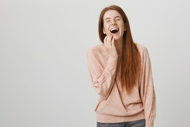 Happy pretty redhead woman laughing, watching comedy