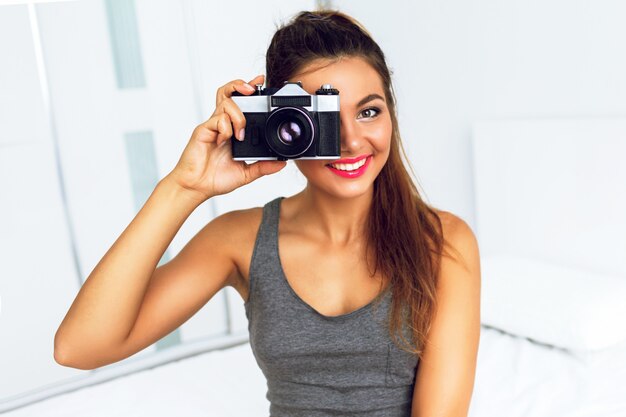 Счастливый довольно улыбающийся фотограф делает снимок с ретро-камерой