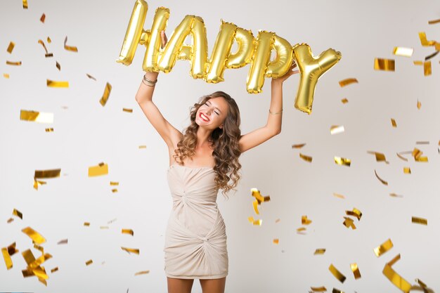 Счастливая красивая женщина празднует новый год в золотом конфетти