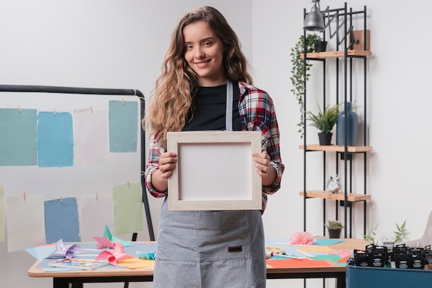 Happy pretty woman holding blank white photo frame