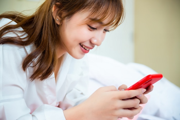 Free photo happy pretty woman using smartphone on the bed