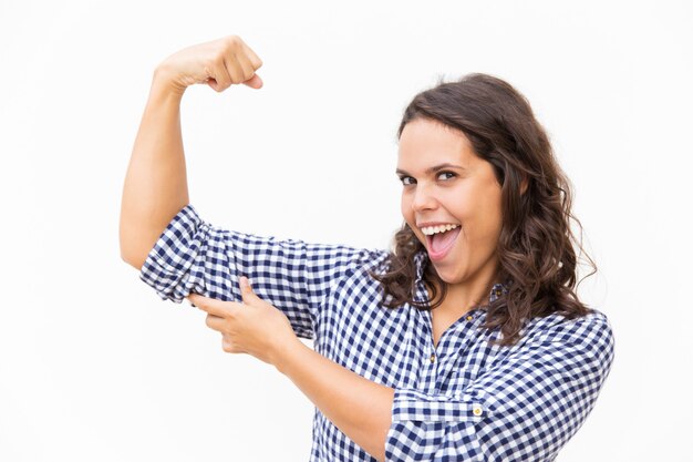 Happy proud woman showing bicep and smiling with open mouth