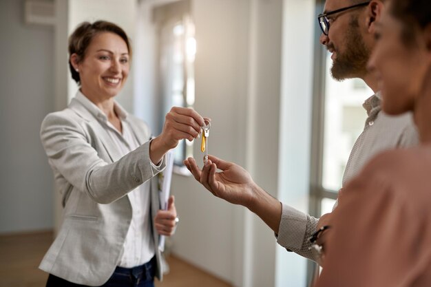 Happy real estate agent giving to a couple keys of their new home