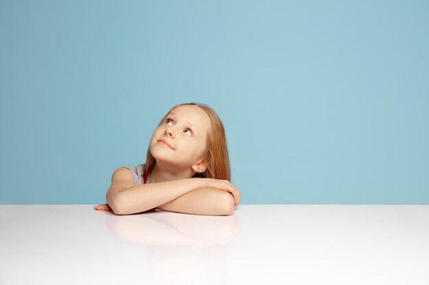 Happy redhair girl isolated on blue studio background Looks happy cheerful sincere Copyspace Childhood education emotions concept