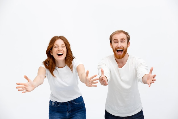 Happy redhead woman and man standing over white wall smiling