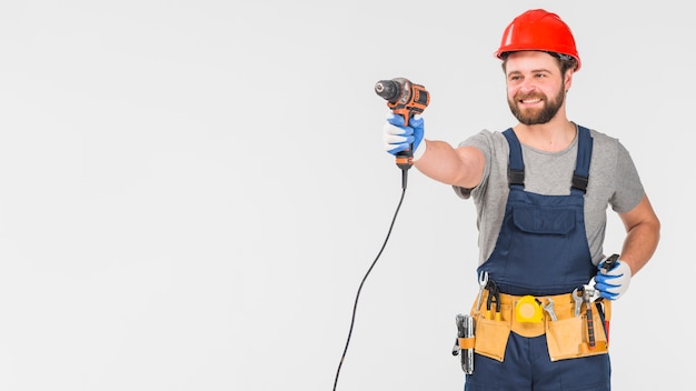 Free photo happy repairman in overall holding drill in hand