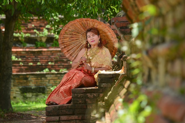 Happy retired woman in the traditional Thai dress travel at the temple.