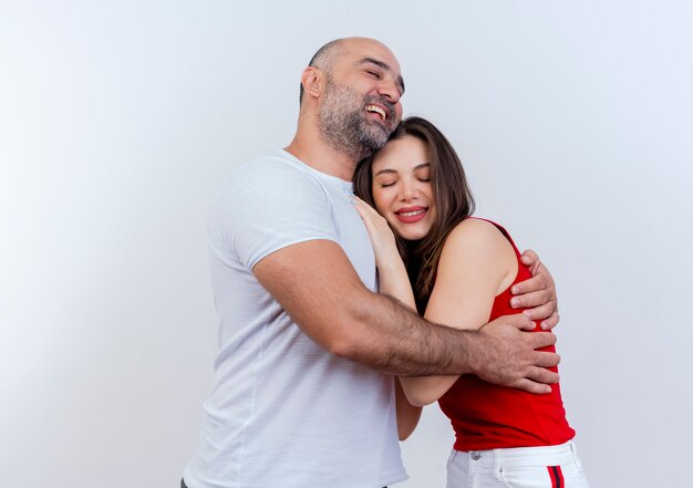 Happy romantic adult couple man hugging woman both smiling with closed eyes isolated on white wall with copy space