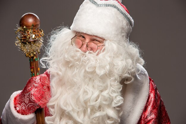 Счастливый Санта-Клаус в очках с персоналом на темном фоне