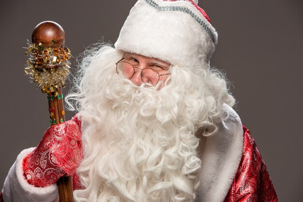 Happy Santa Claus in eyeglasses with staff on dark background