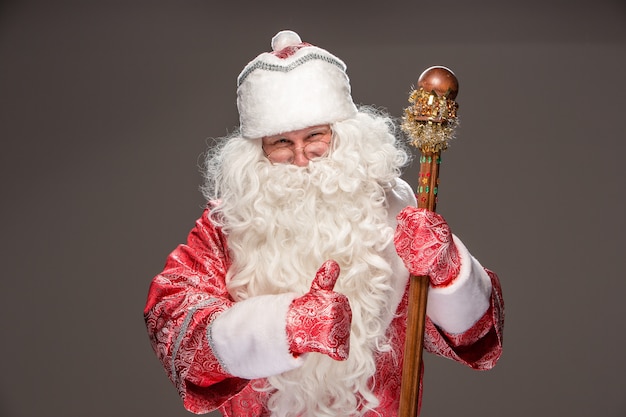 Happy Santa Claus in eyeglasses with staff on dark background
