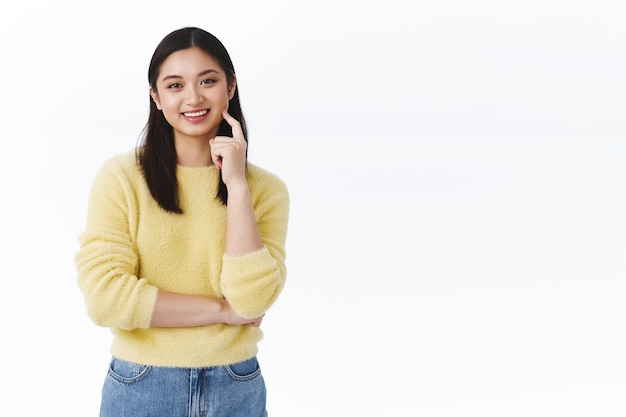 Happy satisfied young female asian student touching clean glowing skin, smiling upbeat