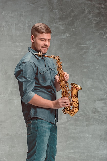 Sassofonista felice con il sax sopra fondo grigio