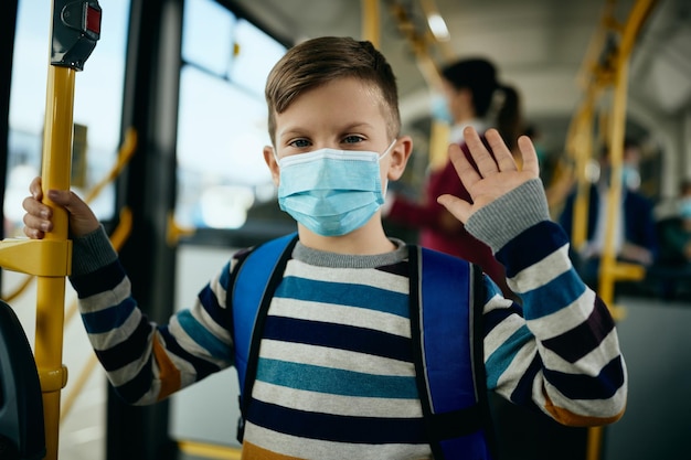 버스로 통근하는 동안 보호용 안면 마스크를 쓴 행복한 남학생