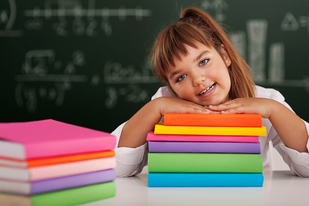 Happy schoolgirl leaning on her books