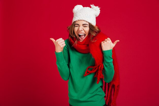 Happy screaming brunette woman in sweater, funny hat and scarf