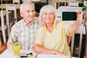 Free photo happy senior couple in cafe taking selfie