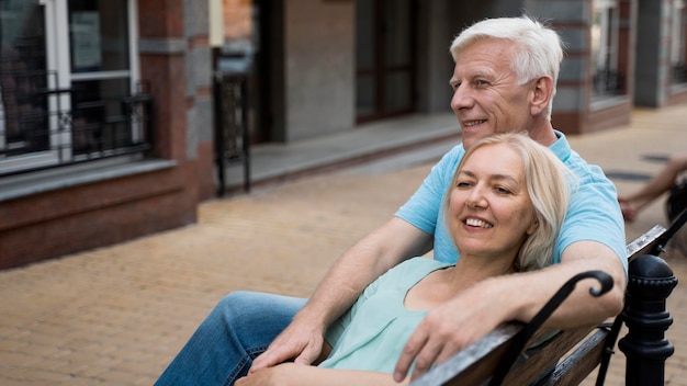 Free photo happy senior couple enjoying their time outdoors on bench