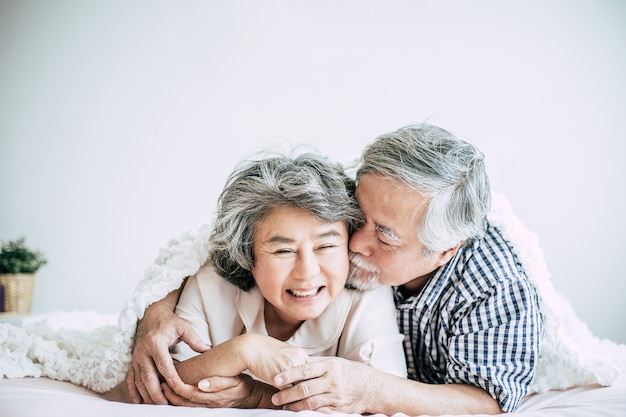 Happy senior couple laughing in bedroom