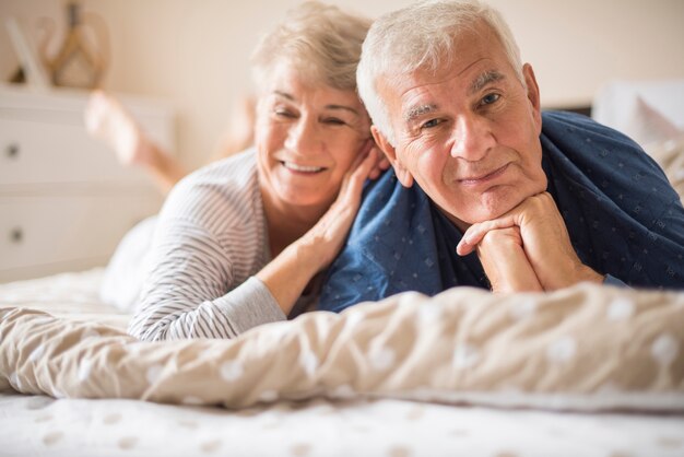 Happy senior couple lying down on the bed