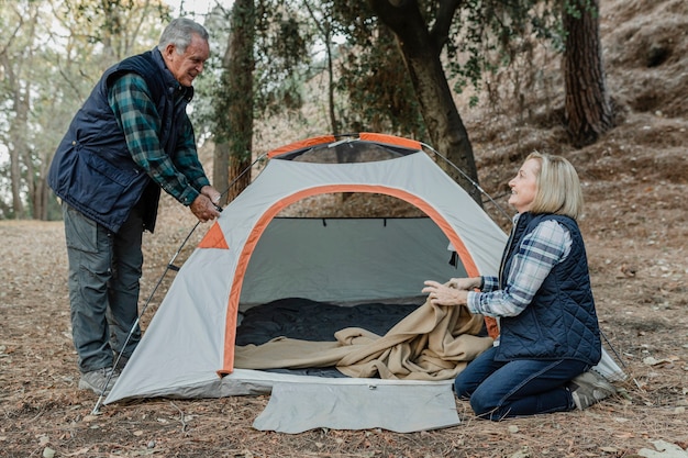 Felice coppia senior, la creazione di una tenda nella foresta