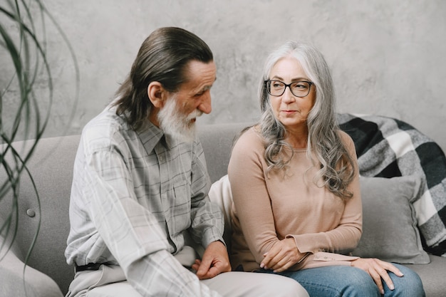 Free photo happy senior couple sitting on couch at home and talking