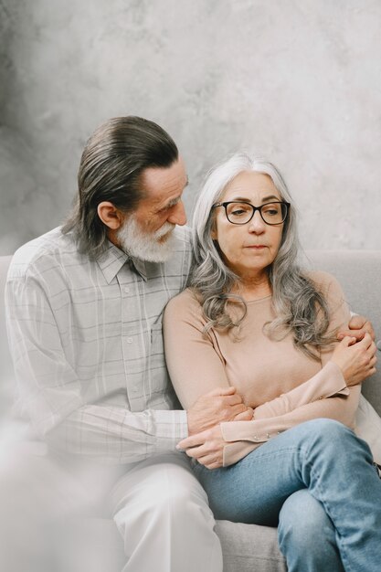 Happy senior couple sitting on couch at home and talking