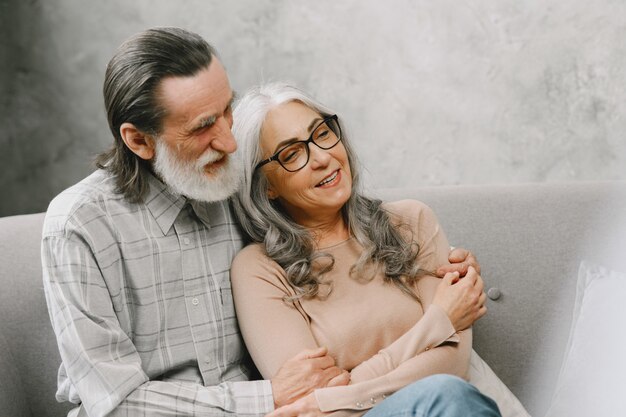 Happy senior couple sitting on couch at home and talking