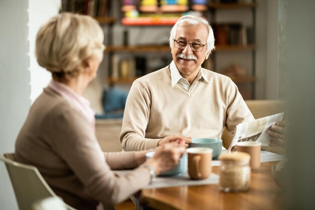 Happy senior couple talking while having a breakfast at dining table Focus is on man