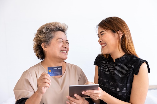 Happy senior elderly Asian woman female mother and daughter enjoy online shopping using digital tablet