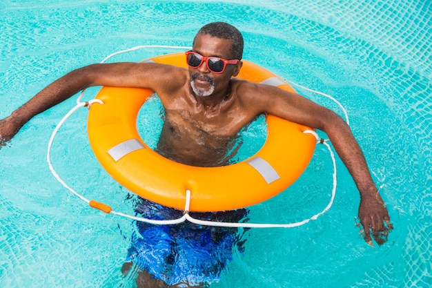 Счастливый старший мужчина, устраивающий вечеринку в бассейне - активный пожилой мужчина, загорающий и расслабляющийся в частном бассейне в летнее время
