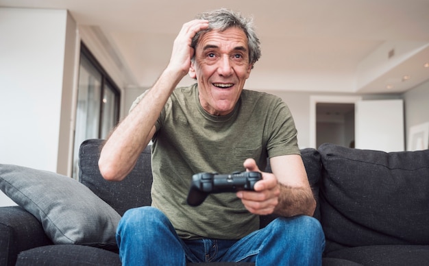 Happy senior man playing video game at home