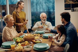 Foto gratuita uomo anziano felice che brinda con la sua famiglia durante il pranzo al tavolo da pranzo