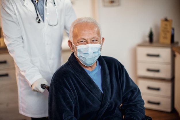 Happy senior man wearing protective face mask at nursing home and looking at camera
