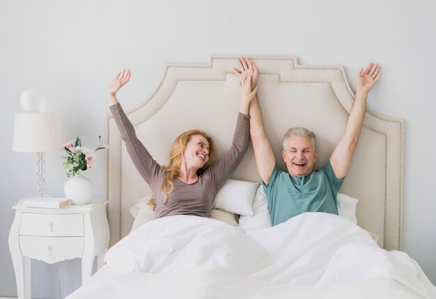 Happy senior man and woman with hands up 