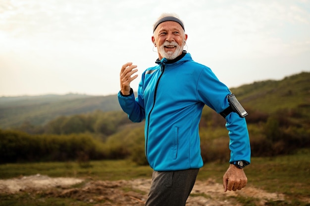 自然の中でジョギングし、健康的なライフスタイルを楽しんで幸せなシニアランナー