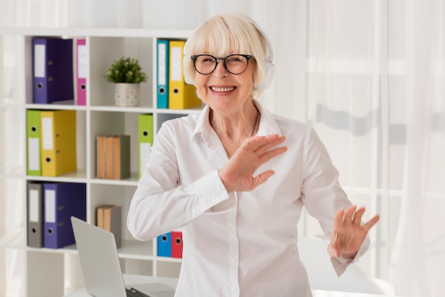 Free photo happy senior standing on her office