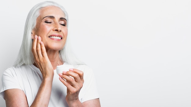 Happy senior woman applying cream