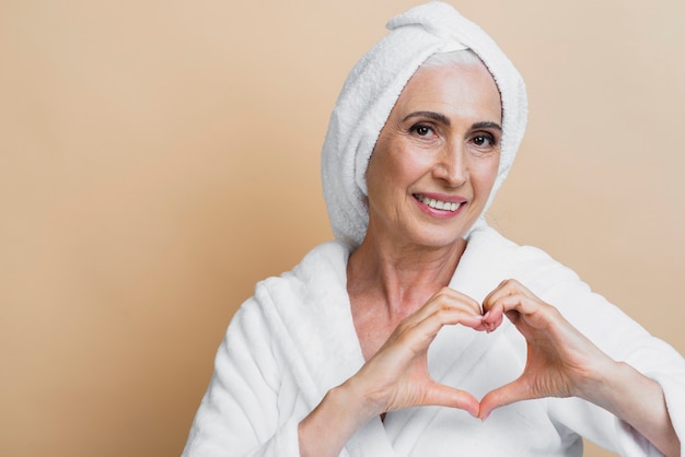 Free photo happy senior woman making heart sign