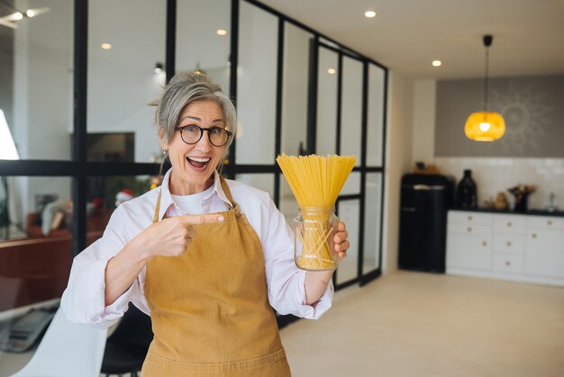 Happy senior woman showing pasta on camera