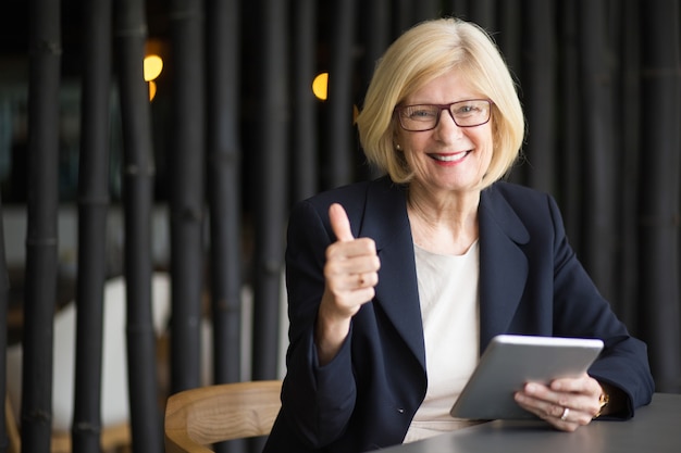 Free photo happy senior woman with tablet in cafe