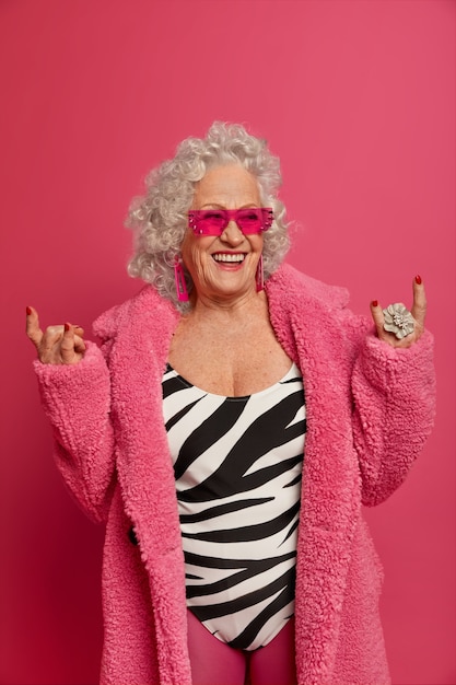 Free photo happy senior wrinkled woman does rock symbol and wears latest fashion trends