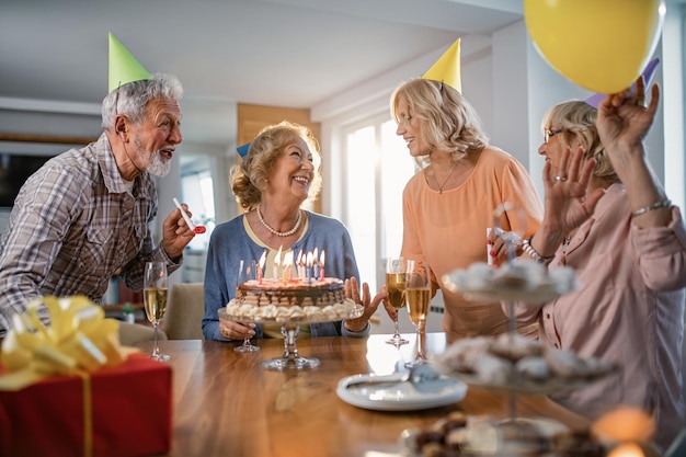 Felice donna senor che parla con i suoi amici e si diverte alla sua festa di compleanno a casa