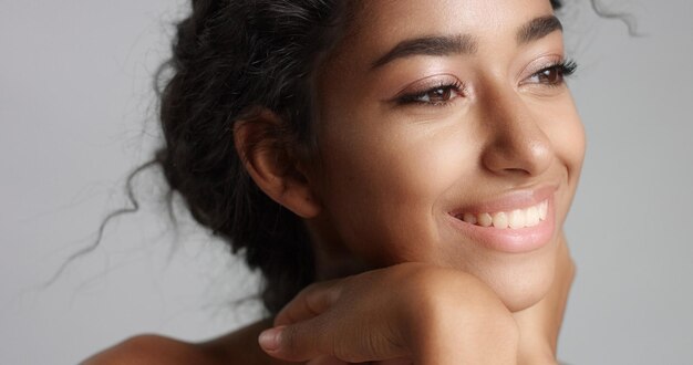 Happy serene young woman with beautiful olive skin and curly hair ideal skin and brown eyes in studio