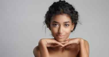 Free photo happy serene young woman with beautiful olive skin and curly hair ideal skin and brown eyes in studio